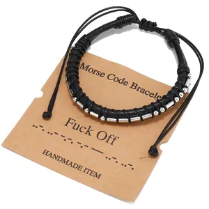 Dettaglio del bracciale con codice Morse con cordino nero e perle argentate su carta