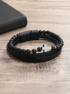 Detalle de una pulsera multicapa para hombre con cuentas negras mates, cruz de plata y cierre imantado