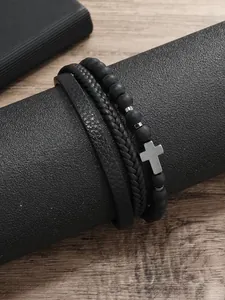 Primer plano de un set de 3 pulseras negras para hombre con cruz y cuero trenzado