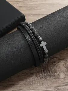 Detalle de pulsera de hombre multicapa con cuero, cordones trenzados y cuentas de piedra con cruz