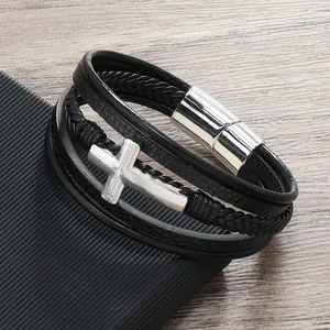 Dettaglio del bracciale in pelle multistrato con ciondolo a croce e chiusura magnetica