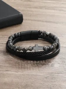 Detalle de una pulsera multicapa de cuentas de piedra para hombre con cruz y cierre imán
