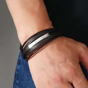 Dettaglio di bracciale multistrato da uomo in pelle marrone con placca in metallo lucido