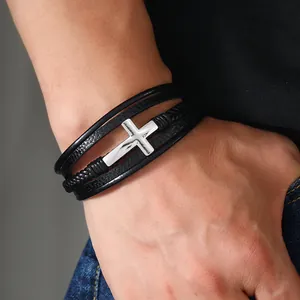 Dettaglio di un bracciale multistrato in pelle nera da uomo con croce in metallo e chiusura