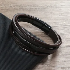 Dettaglio del bracciale multistrato in pelle marrone con chiusura magnetica nera su legno