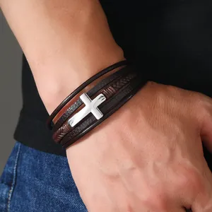 Dettaglio di un bracciale multistrato in pelle da uomo con un ciondolo a croce in metallo