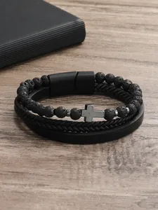 Detalle de pulsera de cuentas de piedra volcánica y cuero trenzado con cruz de metal