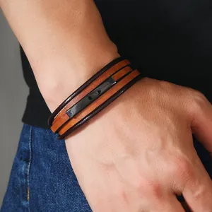 Dettaglio di un bracciale multistrato in pelle da uomo con un ciondolo in metallo nero
