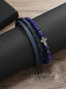 Detalle de pulsera de cuentas azules con cruz junto a cuero y cuerdas trenzadas