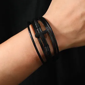 Dettaglio di un bracciale multistrato in pelle nera da uomo con ciondolo a croce retrò