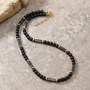 Dettaglio della collana di perline con pietre nere opache e chiusura a moschettone dorata