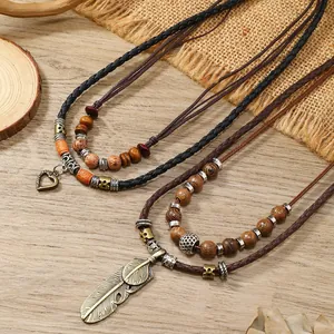 Bohemian multi-layer necklace with wooden beads and feather heart charms on wooden table