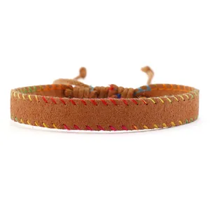 Detail of vintage brown leather bracelet with colorful stitching and adjustable cord