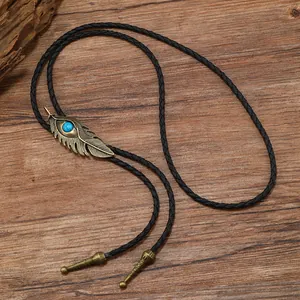 Détail d'une cravate bolo plume en bronze avec pierre turquoise et cordon en cuir tressé