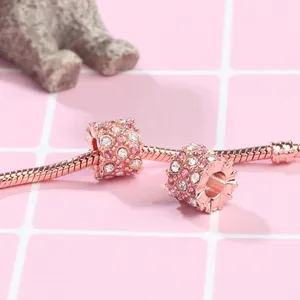Close-up of rose gold charms with pink crystals on a snake chain bracelet