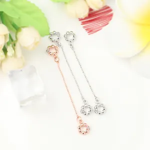 Detailaufnahme langer Kettenohrringe mit Blumenanhängern in Roségold und Silber-Finish