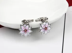 Detalle de pendientes de magnolia en esmalte blanco con cristales rosas brillantes