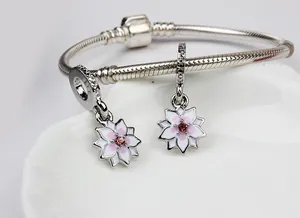 Detalle de pulsera de cadena de serpiente con colgantes de magnolia de esmalte rosa