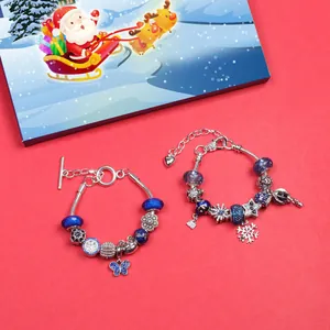 Blaues Weihnachts-Charm-Armband-Set mit Schneeflocken-Anhängern auf rotem Hintergrund
