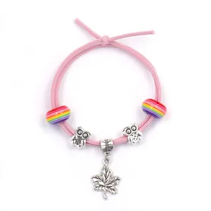 Pink elastic bracelet with rainbow beads, owl sliders and a silver maple leaf charm
