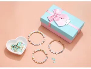 Macro-opname van DIY-sieradenset met polymeerkralen en letterarmbanden in een cadeaudoos