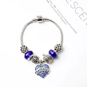 Détail macro du bracelet à breloques en argent avec cristaux bleus et pendentif cœur gravé