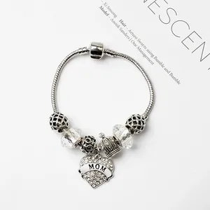 Détail d'un bracelet argenté avec breloques couronne et cœur gravé 'MOM' élégant