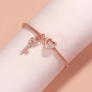 Makroansicht von roségoldenem Schlangenkettenarmband mit Herz- und Schlüsselanhängern