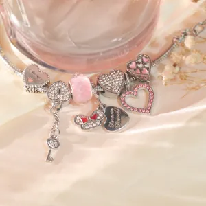 Nahaufnahme eines silbernen Charm-Armbands mit rosa Kristallen und Herzanhängern
