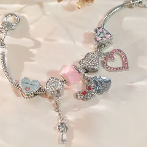 Makroaufnahme von Silber-Charm-Armband mit rosa Kristallherzen und Patenkind-Anhängern