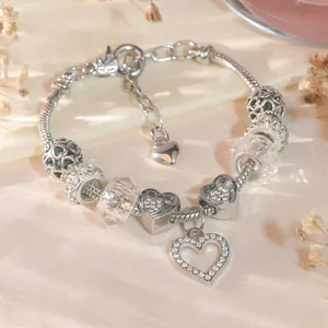 Detail of silver heart beaded bracelet with crystals on soft satin and dried flowers background