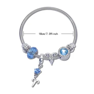 Close-up of silver snake chain bracelet featuring blue crystal beads and Aries zodiac charm