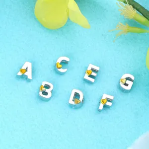 Amuletos de letras A-G con corazones dorados para joyas DIY sobre tela texturizada azul