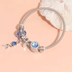 Detail of silver snake chain bracelet with blue crystal beads and heart pendant