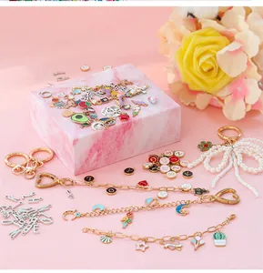 DIY jewelry kit detail featuring enamel charms and golden letters on pink marble tray