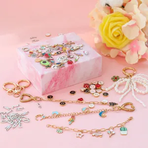 DIY charm bracelet making kit with enamel pendants on pink marble and floral background