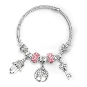 Detalle de pulsera plateada con cuentas de cristal rosa y amuleto de mano de hamsa