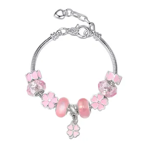 Detalle de dijes de cristal rosa y colgante de trébol en pulsera de cadena de plata