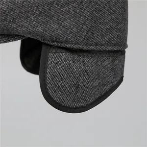 Makroaufnahme von grauem Tweed-Stoff mit schwarzer Paspelierung an der Wintermütze