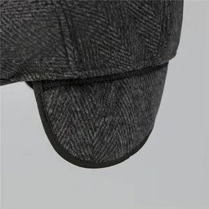 Close-up of grey herringbone flat cap showing warm earflaps and high-quality stitching