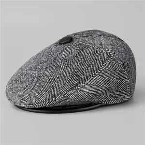 Detail of grey herringbone flat cap with top button and leather-edged brim