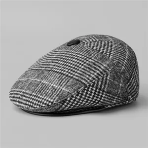 Detail view of winter flat cap showing houndstooth wool fabric and top button texture