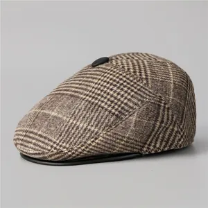 Detail of vintage brown plaid flat cap featuring a black leather brim and decorative button
