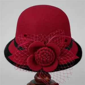 Detail of wool cloche hat with floral mesh veil and feather on a display stand