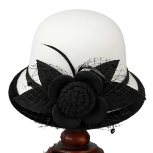 Elegant white wool cloche hat with black mesh flower and feathers on wooden stand