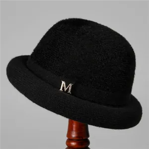 Detailed view of black knitted winter hat with rhinestone M metal accessory