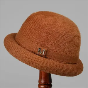 Detail of a brown knit winter hat for women with plush texture and jeweled M accessory
