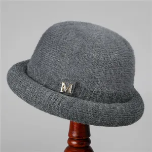 Detail of dark grey cashmere knit hat with sparkling rhinestone M metal ornament