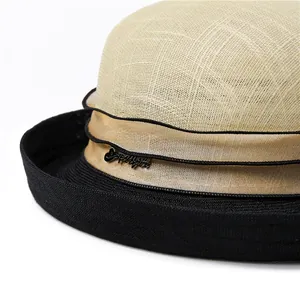 Detailed close-up of straw hat crown with wavy ribbon and black metallic letter buckle