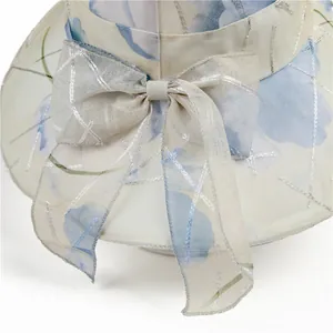 Detail of elegant organza sun hat with blue floral prints and large bow accent